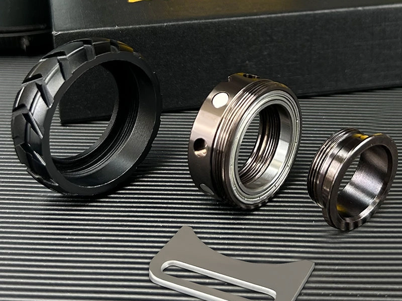 A close-up of disassembled fidget ring components, showcasing a high-quality metal design with intricate details, placed on a textured black surface.