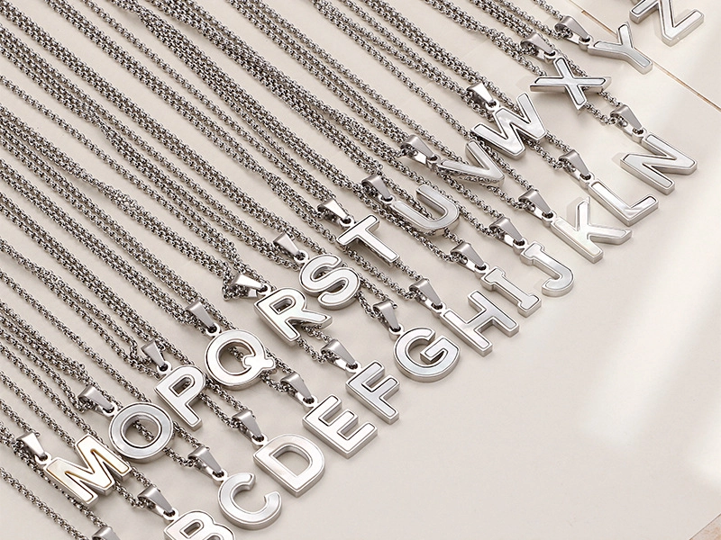 A close-up view of stainless steel alphabet necklaces, showcasing their polished, smooth, and skin-friendly surface.
