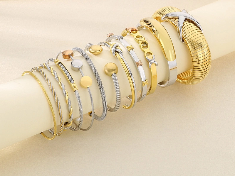 A stylish collection of stainless steel bangle bracelets in gold and silver finishes, featuring twisted, smooth, and textured designs.