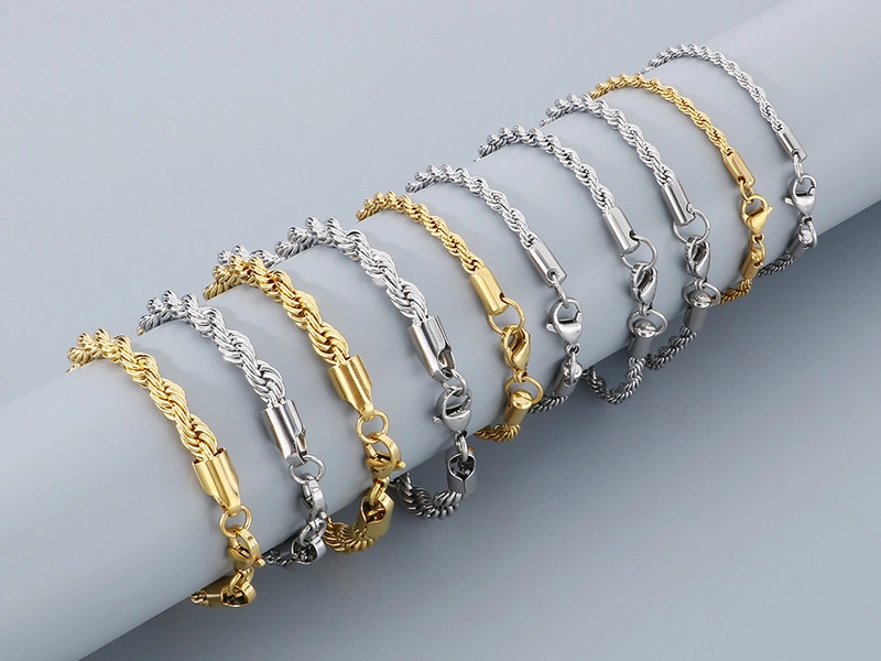 A collection of stainless steel rope chain bracelets in gold and silver tones, elegantly displayed on a cylindrical surface.