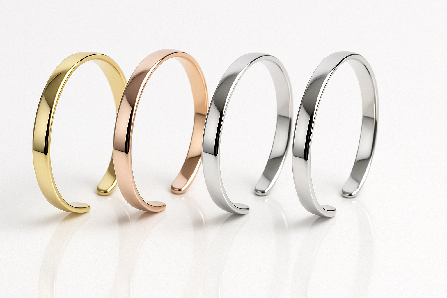 Row of polished metal cuff bracelets in gold, rose gold, and silver, showcasing mirror-finish burnishing under uniform lighting.