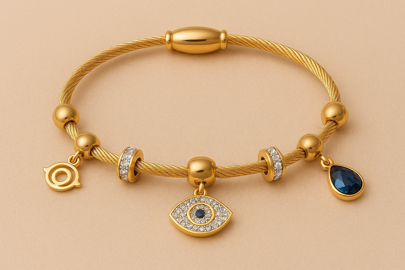 Gold wire charms bracelet featuring crystal-studded beads, evil eye charm, and blue teardrop gemstone pendant.