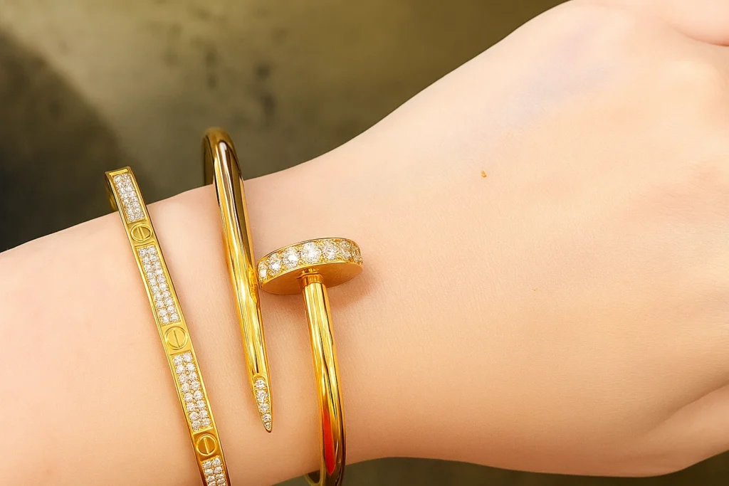 Close-up of a wrist wearing a gold Juste un Clou bracelet and a diamond-studded Love bracelet, showcasing modern luxury jewelry.