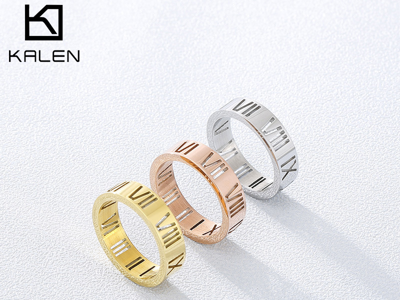 Three stainless steel rings in gold, rose gold, and silver finishes, engraved with Roman numerals, displayed on a light background.